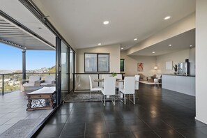 A modern kitchen with a dining area, a large window, and a view of the city. - Oceanview Oasis - Close to CBD and Airport (Sandy Bay)