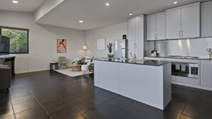 A modern kitchen with a central island, built-in appliances, and a large window providing natural light. - Spacious Sandy Bay Retreat with Water Views (Sandy Bay)