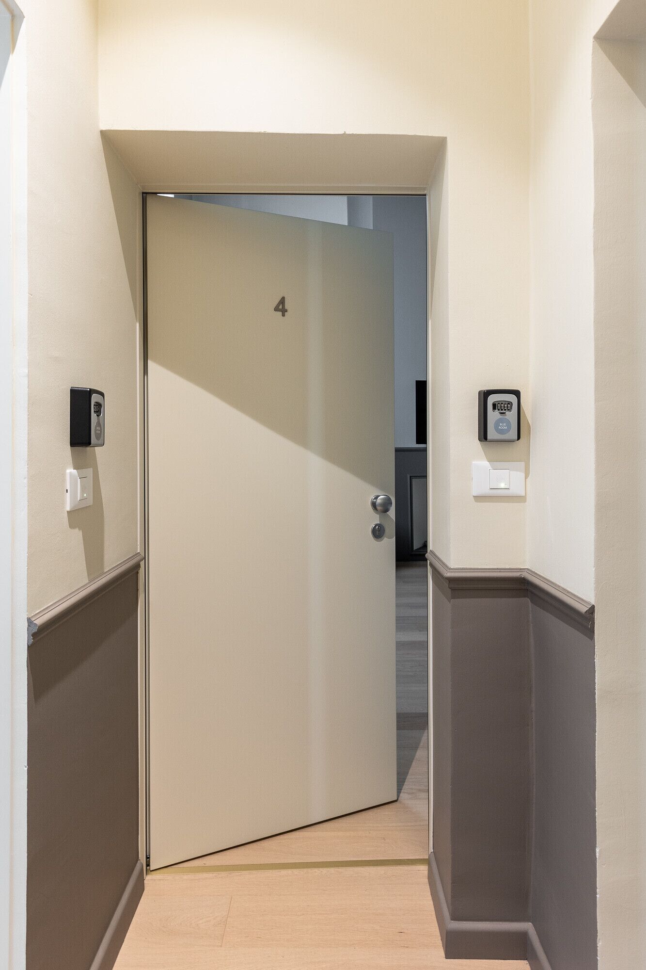 A hallway with a door marked with the number 4, a doorbell, and a light switch on the wall.