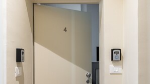 A hallway with a door marked with the number 4, a doorbell, and a light switch on the wall. - Suite Blue by Wonderful Italy (Bologna)