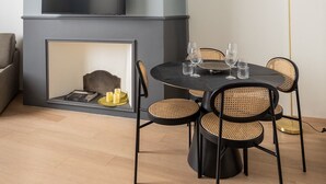 A modern living room with a fireplace, a flat-screen TV, a dining table with chairs, and a floor lamp. - Suite Blue by Wonderful Italy (Bologna)