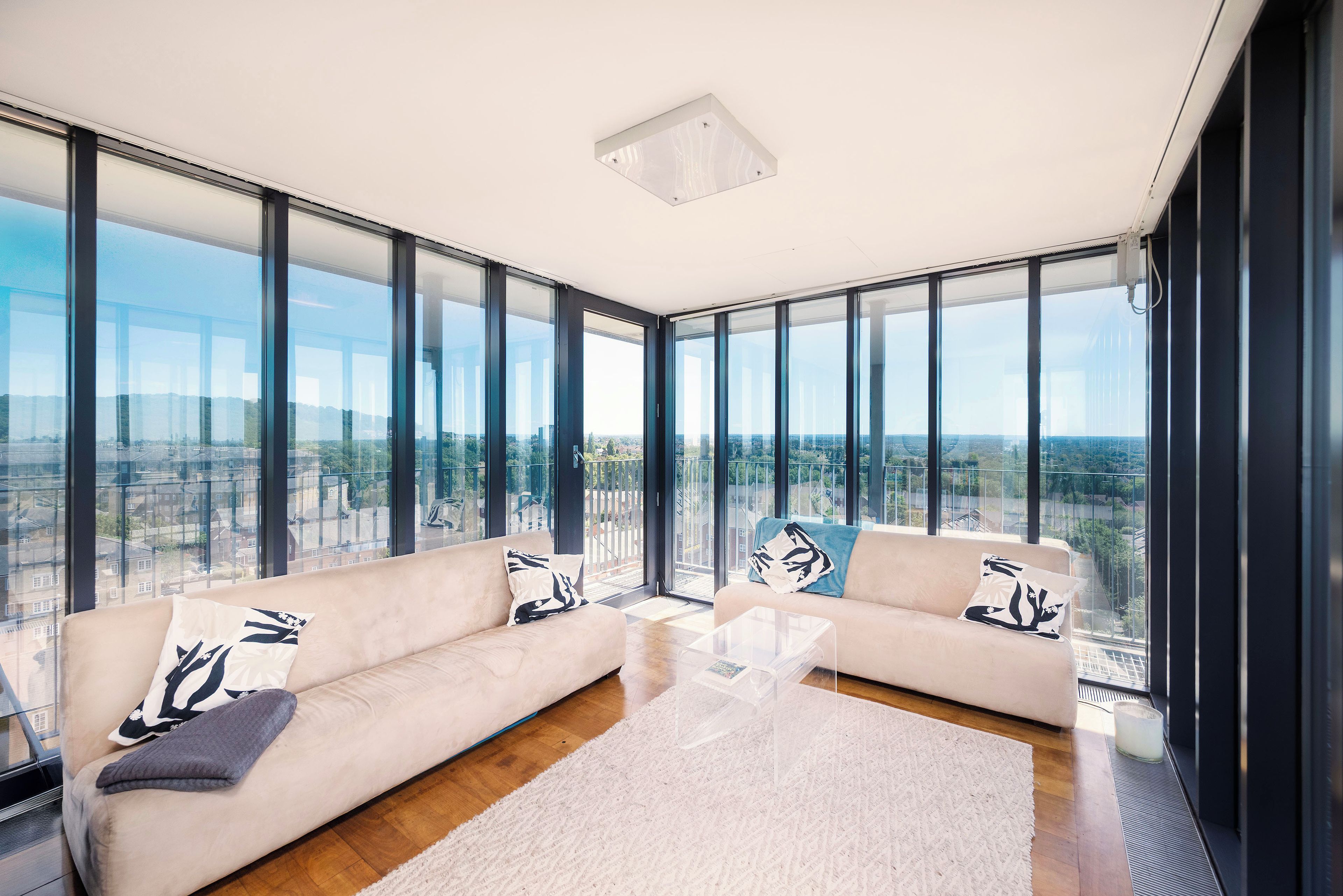 A modern living room with two sofas, a coffee table, and large floor-to-ceiling windows offering a city view.