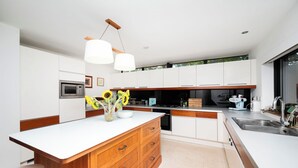A modern kitchen with white cabinetry, a wooden island, and a built-in oven. - Historic 3BDR with Sky Lounge in Greenwich (Greater London)