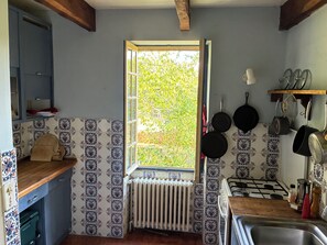 A kitchen with a window, tiled backsplash, wooden countertop, and hanging pots. - Bread Oven. Peace and quiet in rural Lot. (Uzech)