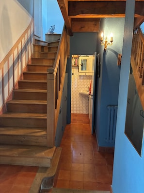A wooden staircase leading to a kitchen area with a tiled floor, a sink, and a cabinet with a mirror. - Bread Oven. Peace and quiet in rural Lot. (Uzech)