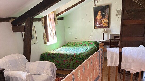 Una habitación con una cama, un sofá, una escalera de madera y un cartel en la pared.