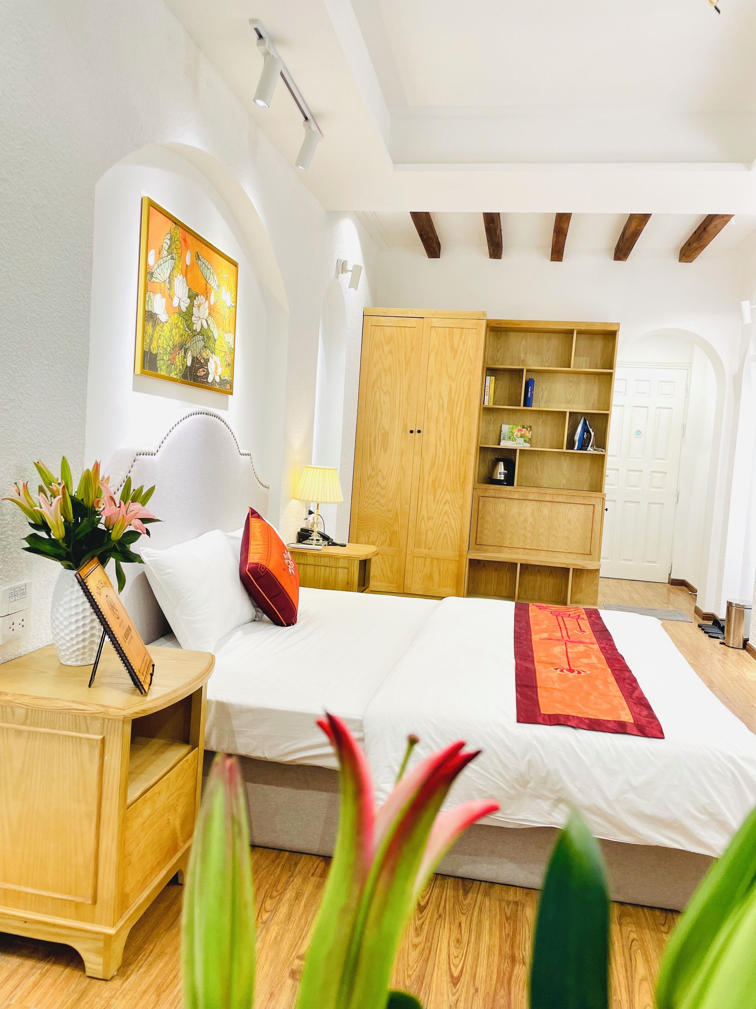 A bedroom with a bed, bedside tables, a wardrobe, and a painting on the wall.