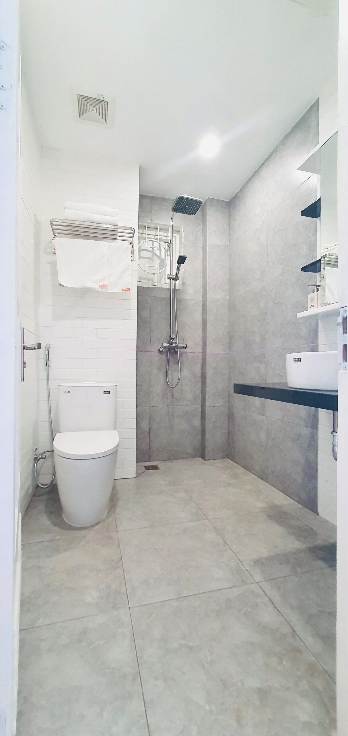 A modern bathroom with a toilet, a shower, and a sink.