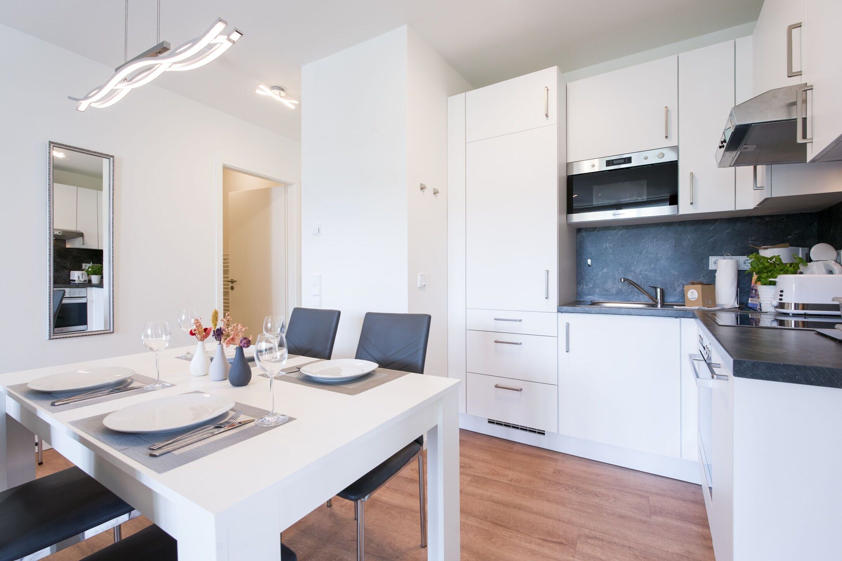 Een moderne keuken met witte kasten, een ingebouwde oven en een roestvrijstalen afzuigkap.