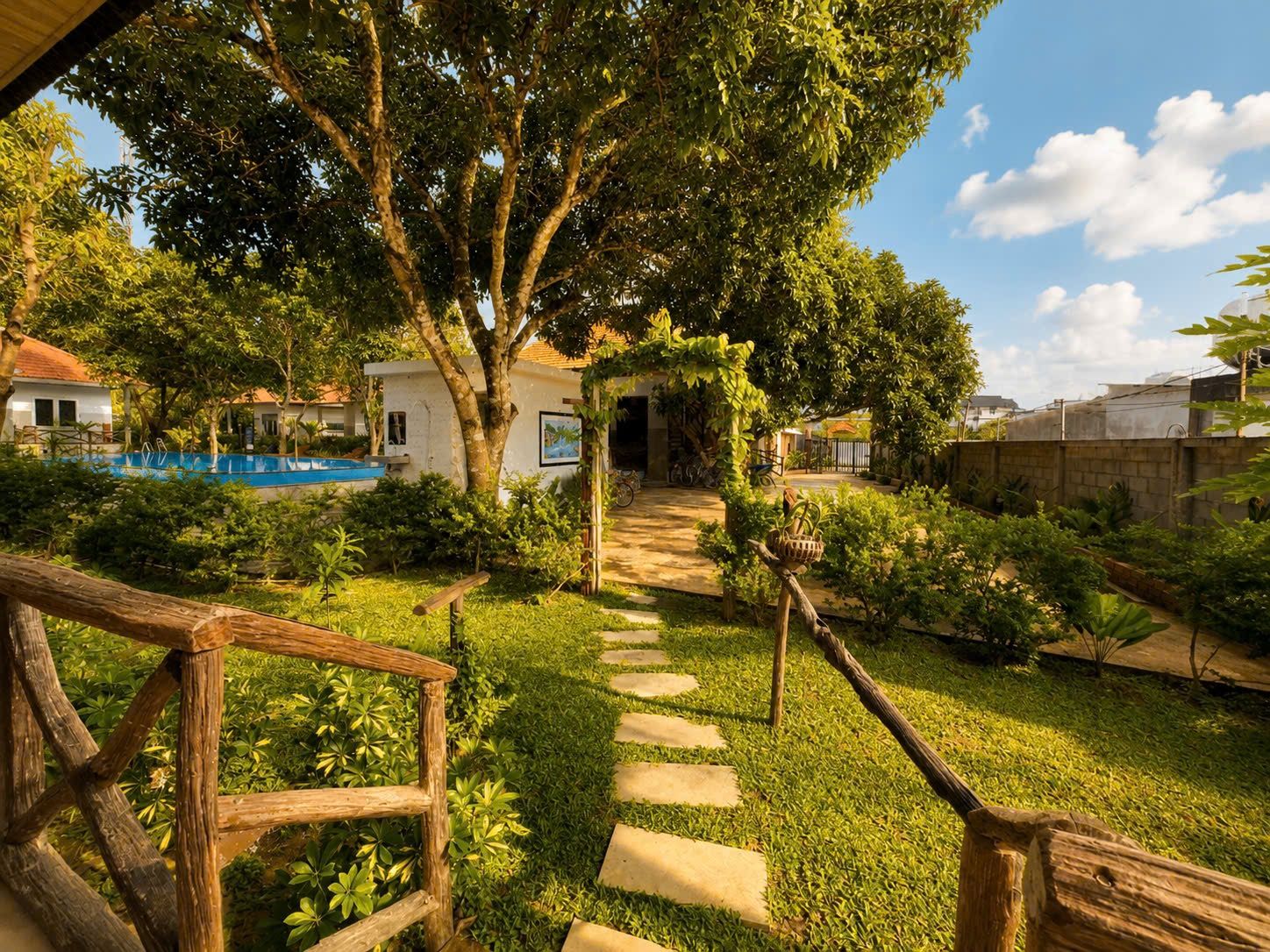 A pathway leading to a building with a pool and surrounded by lush greenery.