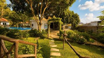 A pathway leading to a building with a pool and surrounded by lush greenery.