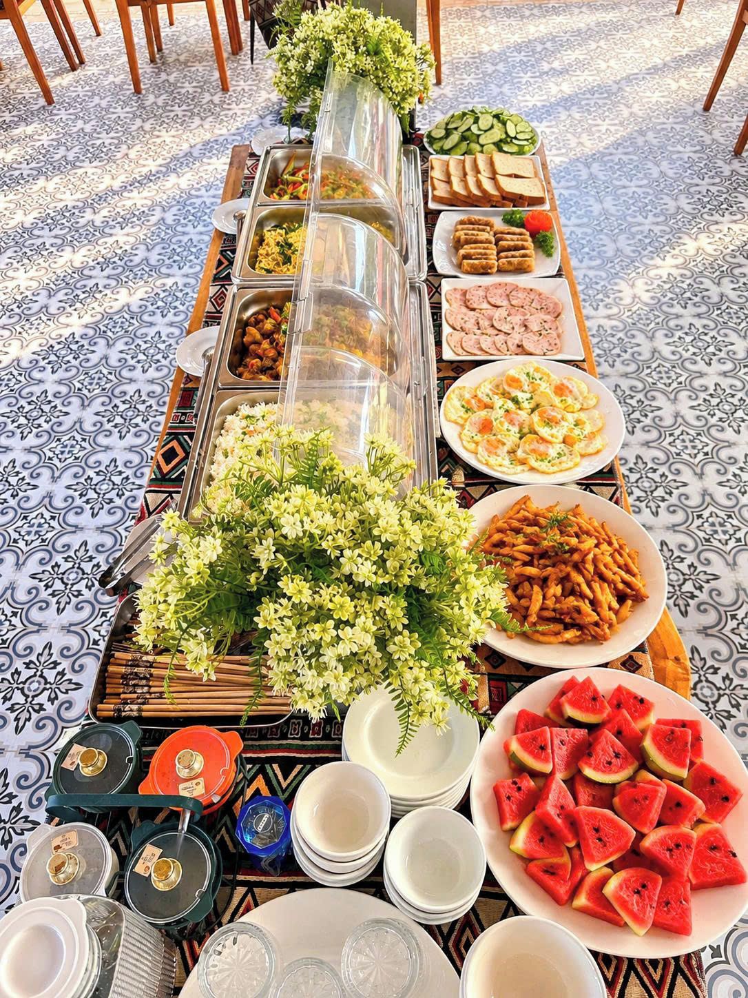A buffet table with various food items and a floral centerpiece.