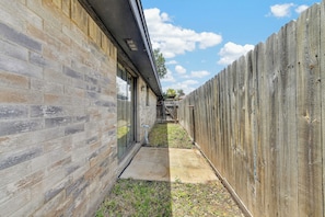Une ruelle étroite, bordée d’un côté d’un mur de briques et de l’autre d’une clôture en bois.