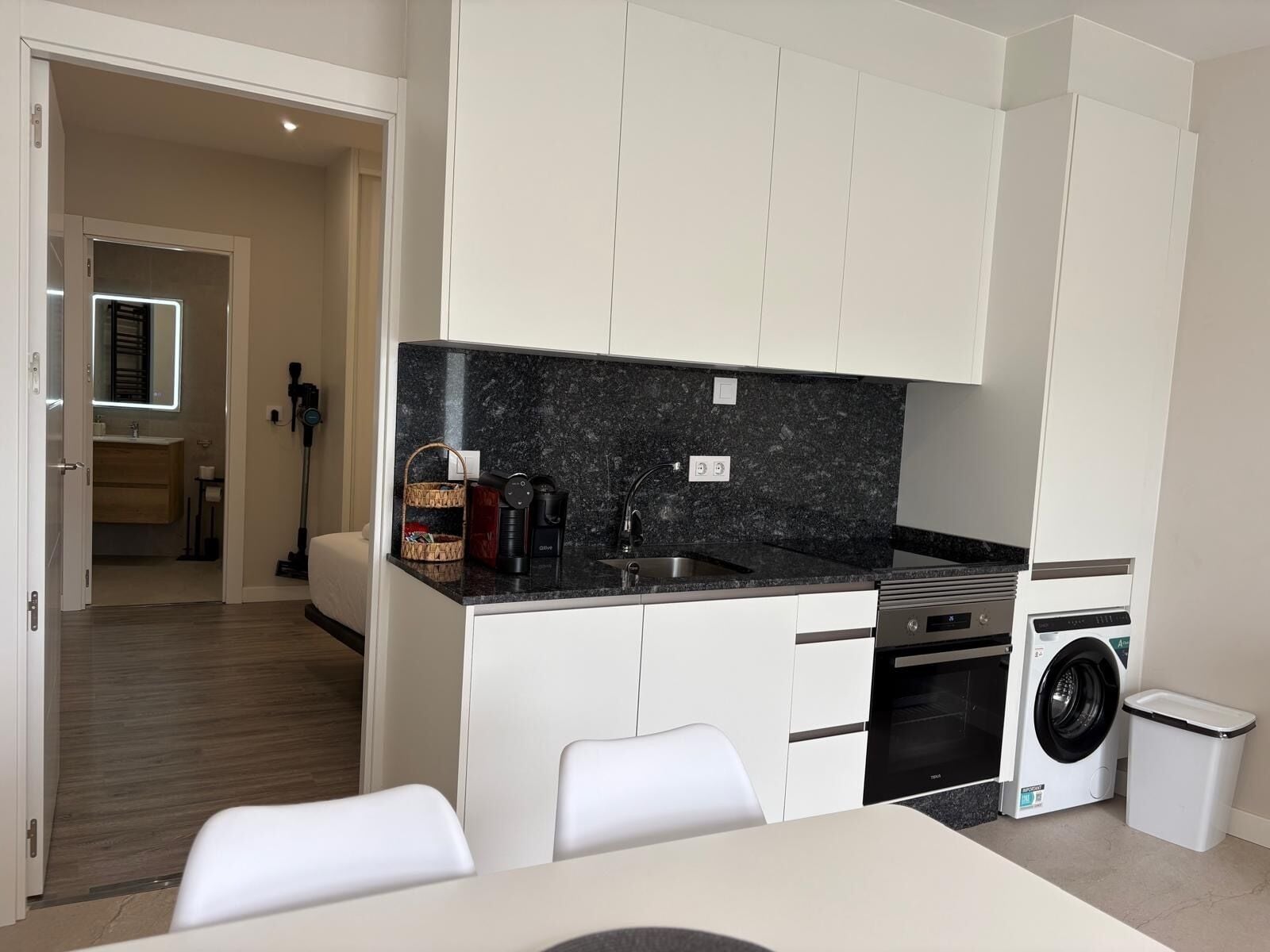 A compact kitchen with a built-in washing machine, a coffee maker, and a microwave.