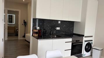 A compact kitchen with a built-in washing machine, a coffee maker, and a microwave.
