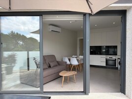 Um interior moderno com sofá, cadeiras e mesa de jantar perto de uma porta de vidro deslizante.