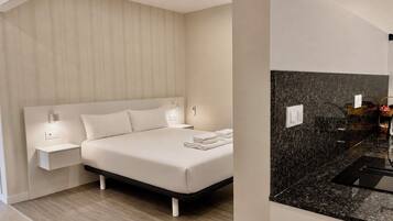Una habitación de hotel moderna con una cama grande, mesitas de noche y un baño con encimera negra.