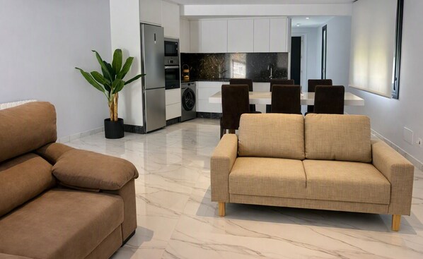 A modern living room with a sofa and a dining area with chairs.