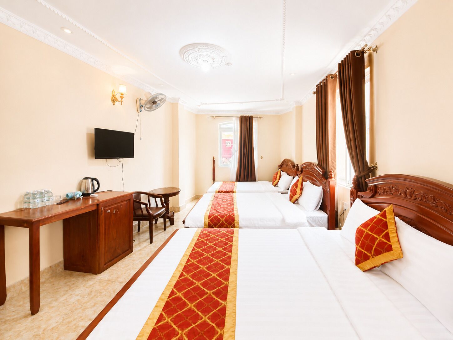 A hotel room with a bed, a desk, a chair, a television, and a window with curtains.