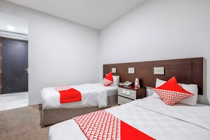 A hotel room with two beds, a wooden headboard, a bedside table with a phone, and a door. - Collection O Loc Binh Hotel Near Da Lat (Xuan Huong Ward, Da Lat)