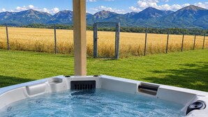 A hot tub with a view of mountains and a field.