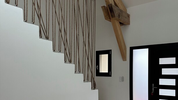 A staircase with wooden beams and a black door with frosted glass panels.