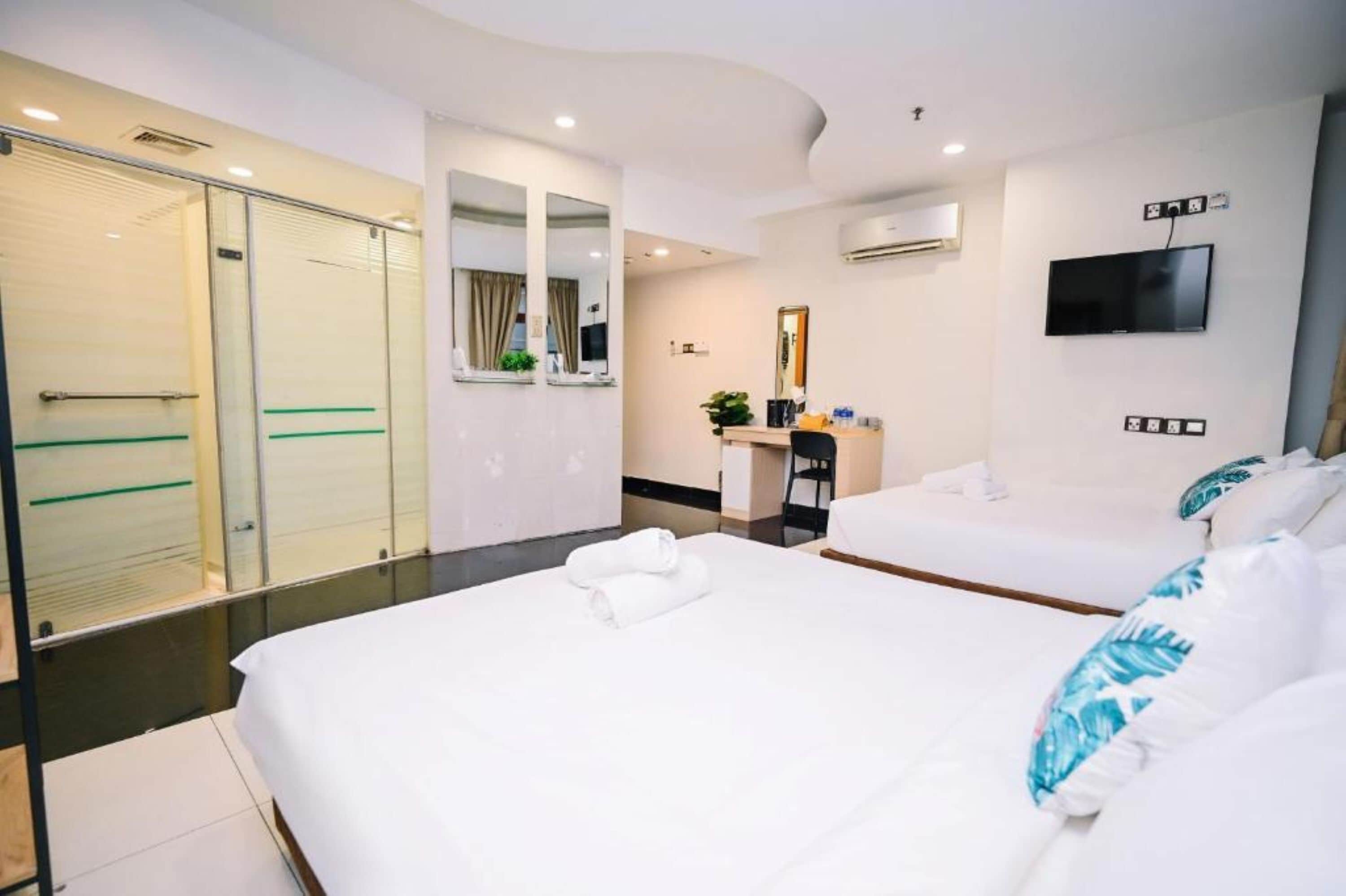 A hotel room with a bed, a desk, a chair, a TV, and a sliding door.