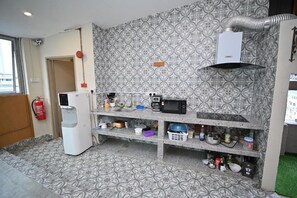 A compact kitchen with a microwave, coffee maker, and a water dispenser. There is a fire extinguisher mounted on the wall, and a patterned backsplash. - Swing & Pillows @ Central Market Kuala Lumpur (Kuala Lumpur)