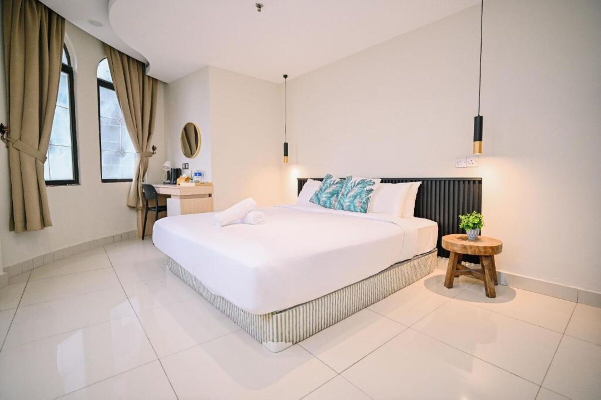 A hotel room with a large bed, a desk, and a chair.