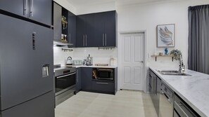 A modern kitchen with dark cabinets, stainless steel appliances, and a marble countertop. - Coastal Clover - 7 James Drive (Carrickalinga)