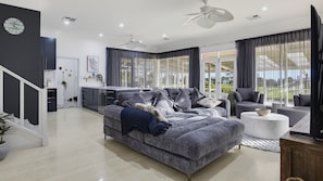Ein modernes Wohnzimmer mit einem grauen Sofa, einem weißen Couchtisch und einem Essbereich mit einer Küche im Hintergrund.