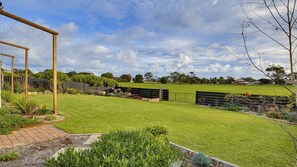 A well-maintained backyard with a wooden pergola, a fenced area, and a variety of plants. - Coastal Clover - 7 James Drive (Carrickalinga)