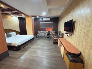 Ein Hotelzimmer mit Bett, Sofa, Fernseher und Schreibtisch.