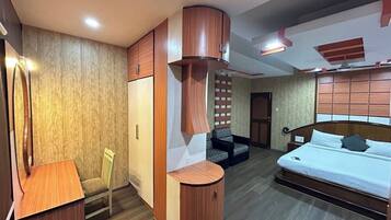 Una habitación de hotel con cama, escritorio, silla y armario.