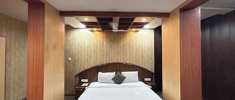 A hotel room with a large bed, wooden headboard, and a ceiling fan.
