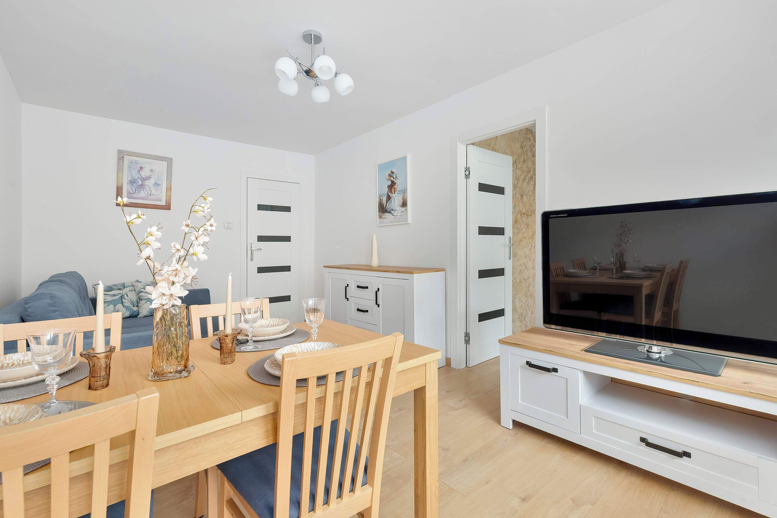 A modern living room with a dining table, chairs, a TV, and a sofa.