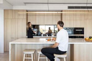 A modern kitchen with a central island, bar stools, and a view of the outdoors. - Modern 2BR Apartment within Prestigious Bellevue Hill (Bellevue Hill)