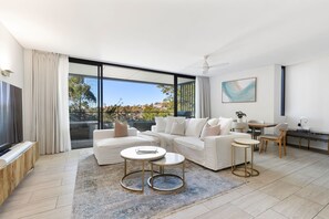 A modern living room with a large window, white sofas, a coffee table, and a dining area. - Modern 2BR Apartment within Prestigious Bellevue Hill (Bellevue Hill)