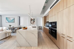 Uma cozinha moderna com ilha de mármore, armários de madeira e eletrodomésticos de aço inoxidável.