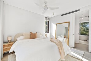 Ein Schlafzimmer mit einem Bett, einem Nachttisch, einer Lampe und einem großen Spiegel.