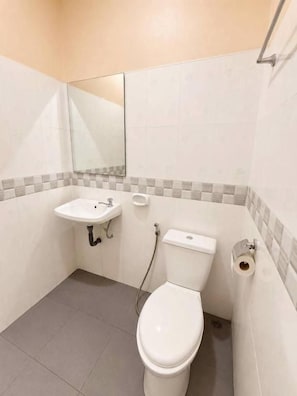Pieni kylpyhuone, jossa on wc, pesuallas ja peili.
