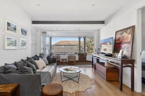Ein modernes Wohnzimmer mit grauem Sofa, einem Couchtisch und Blick ins Freie.