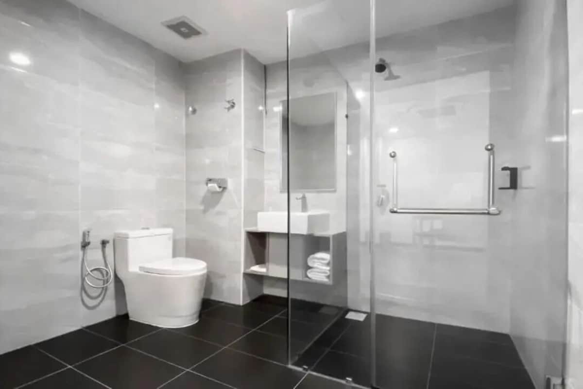 A modern bathroom with a glass-enclosed shower, a toilet, and a sink.