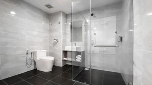 A modern bathroom with a glass-enclosed shower, a toilet, and a sink.