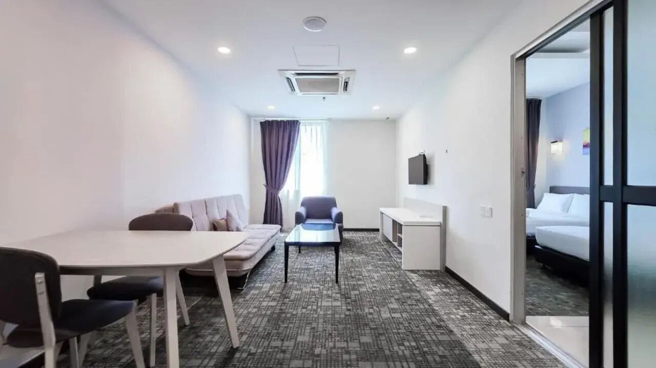 A hotel room with a bed, a desk, a chair, a sofa, and a small table.