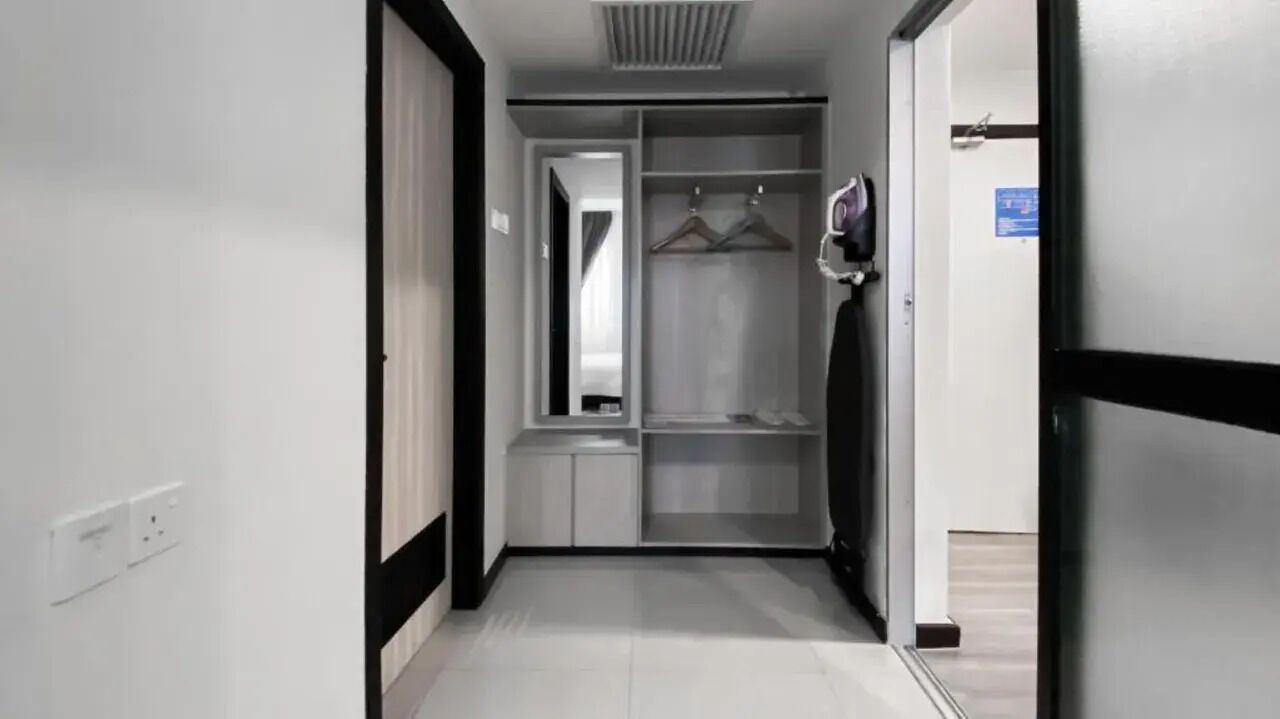 Un pasillo que conduce a un armario con espacio para colgar y un espejo.