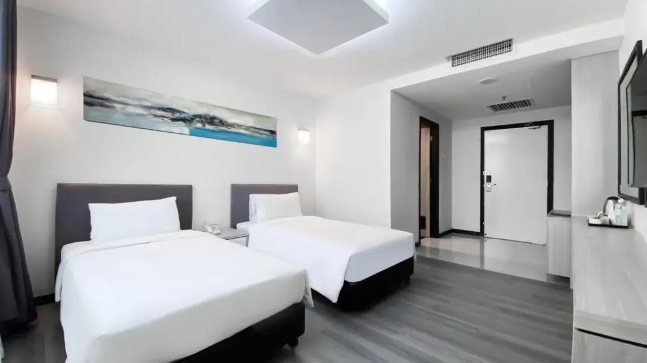 Habitación de hotel con dos camas, un cuadro en la pared, un escritorio y un espejo.