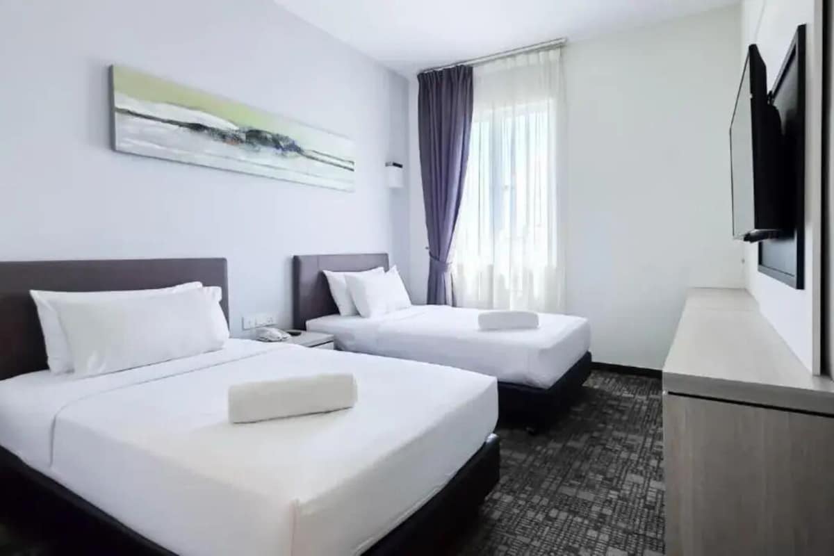 A hotel room with two beds, a flat-screen TV, and a painting on the wall.