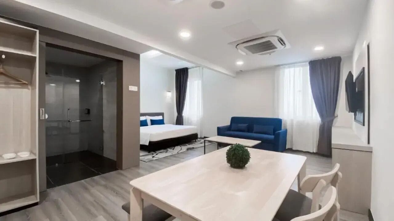 Una camera d'albergo moderna con un letto, un divano blu, un tavolo da pranzo e un armadio a tutta parete.