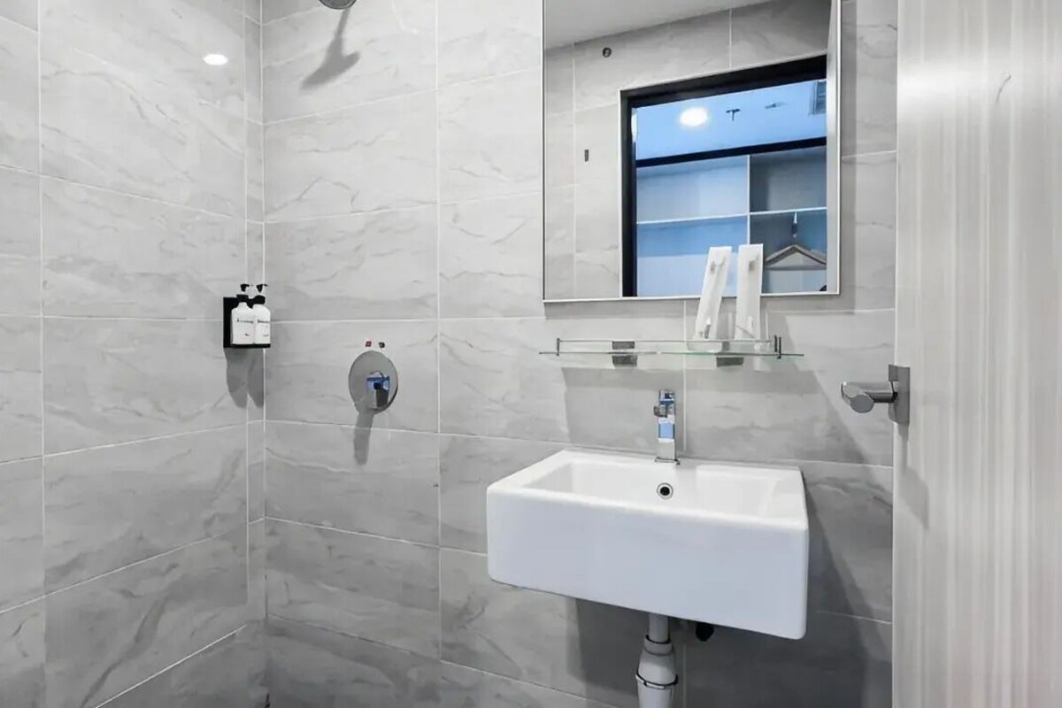 A modern bathroom with a white sink, a glass shelf, and a mirror above it.